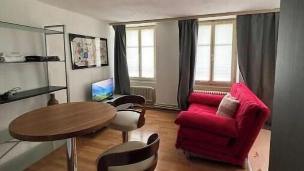 A living room with a red sofa, a round table, and a TV.