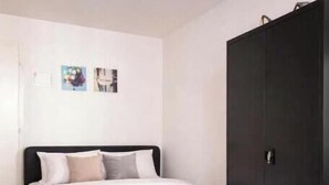 Ein Schlafzimmer mit einem Bett, einem Kleiderschrank und einer Wand mit zwei Bildern.