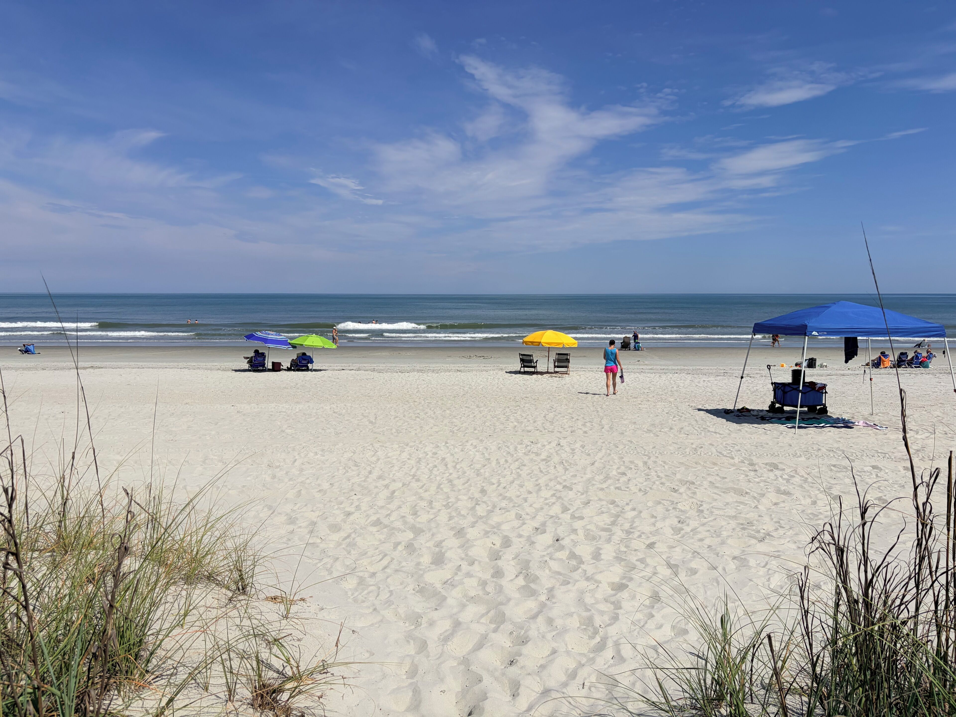 A beach with umbrellas, chairs, and a tent.