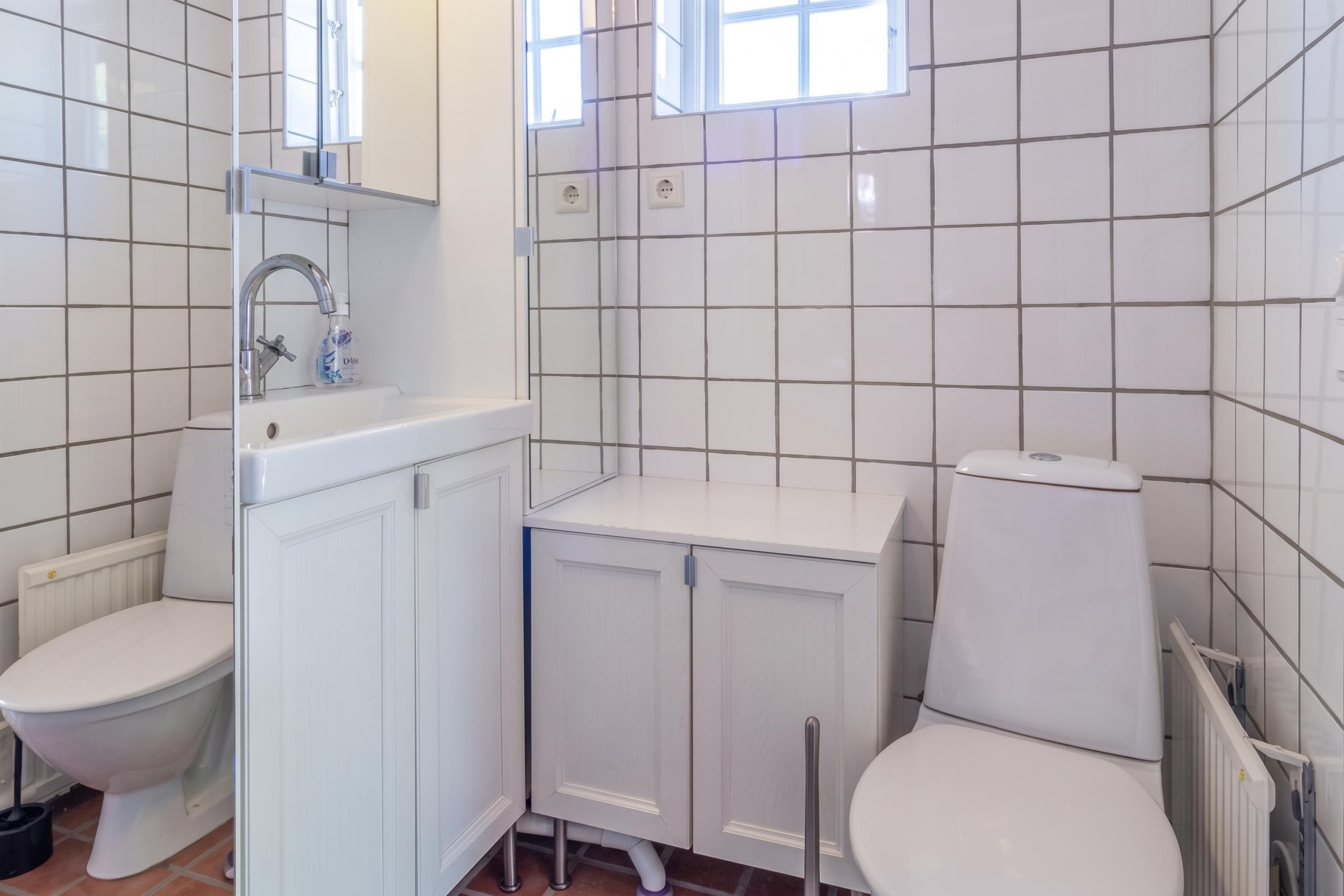 A bathroom with a toilet, sink, and mirror.