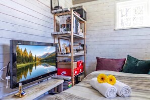 A bedroom with a bed, a TV, a wooden bookshelf, and a window with a view of a lake. - The Aspö Hideaway (Drottningskär)