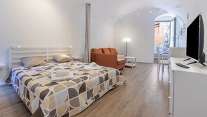 A modern hotel room with a bed, a sofa, a desk with a TV, and a lamp. - Palma Cabin Renovated Flat Old Town (Sanremo)