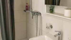 Ein Badezimmer mit Dusche, Waschbecken und Spiegel.