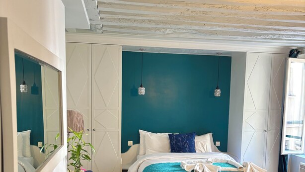 Un dormitorio con cama, sofá, espejo y ventana.