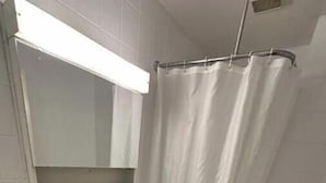 Een badkamer met een wit wastafelmeubel, een spiegel erboven, een douchegordijn en een toilet.
