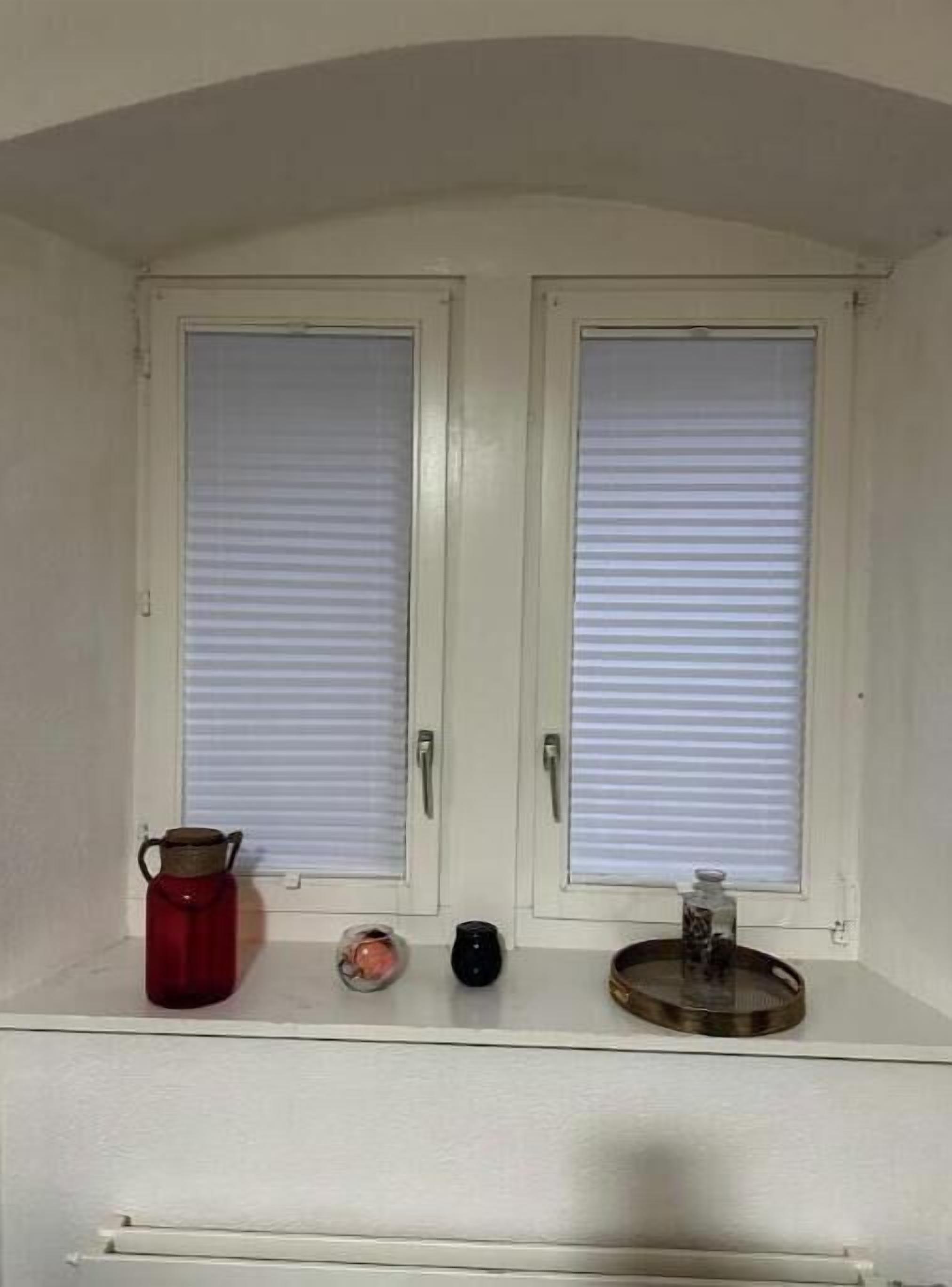 Ein Zimmer mit zwei weißen Türen, einem roten Wasserkocher, einem kleinen rosa Gegenstand, einem schwarzen Gegenstand und einem runden Gegenstand auf einem Regal.