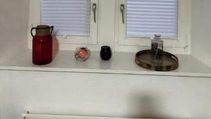 Een kamer met twee witte deuren, een rode waterkoker, een klein roze voorwerp, een zwart voorwerp, en een rond voorwerp op een plank.