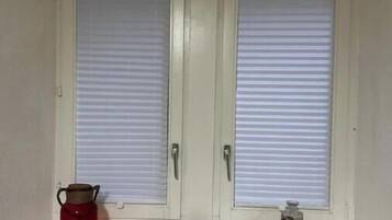 Ein Zimmer mit zwei weißen Türen, einem roten Wasserkocher, einem kleinen rosa Gegenstand, einem schwarzen Gegenstand und einem runden Gegenstand auf einem Regal.