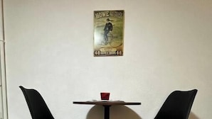 Een kamer met twee zwarte stoelen en een tafeltje met een rode beker.