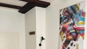 Ein rotes Sofa mit mehreren Kissen, ein grüner Sessel, ein kleiner runder Tisch und ein Bild an der Wand.