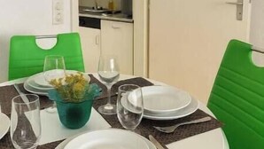 Ein Essbereich mit einem runden Tisch, grünen Stühlen, weißen Tellern und einer Blumenvase.