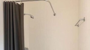 Eine Dusche mit Duschvorhang, eine Badewanne und eine weiße Wand.