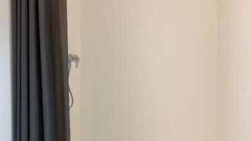 Eine Dusche mit Duschvorhang, eine Badewanne und eine weiße Wand.