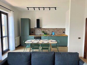 Eine moderne Küche mit Esstisch für vier Personen, einem eingebauten Backofen und einem Fenster mit Vorhängen.