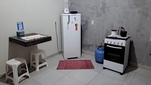 Une cuisine compacte équipée d’un réfrigérateur, d’une cuisinière et d’une bouteille de gaz.