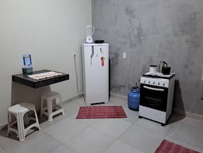 Een kleine keuken met een koelkast, fornuis en gasfles.