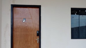 Une porte en bois avec un cadre noir, une petite fenêtre donnant sur un paysage, et un panneau indiquant le numéro « 2 » sur la porte.