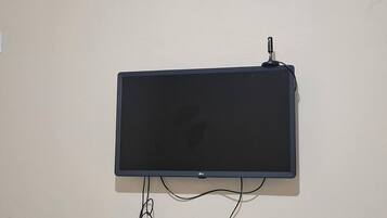 Televisão de tela plana presa na parede, com um cabo conectado.
