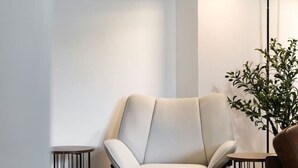 A corner room with a white chair, a small table, a floor lamp, and a plant. - Forth Court City Retreat (Stirling)
