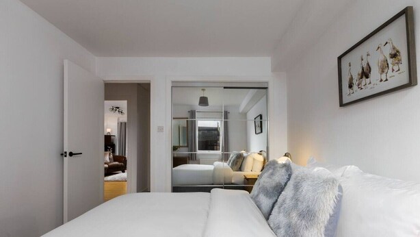 A modern hotel room with a large bed, a view into the adjacent room, and a framed artwork on the wall. - Forth Court City Retreat (Stirling)