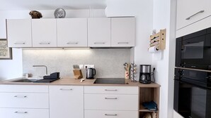 A modern kitchen with white cabinets, a wooden countertop, a sink, a coffee maker, and an oven.
