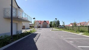 A residential street with houses, a clear sky, and a parking area.