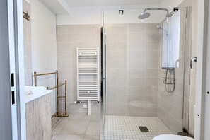Et moderne badeværelse med brusebad, håndklæderække og toilet.