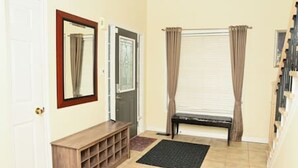 A hallway with a wooden console, a door, a window with curtains, and a radiator. - The Peaceful Court House in Kitchener (Kitchener)