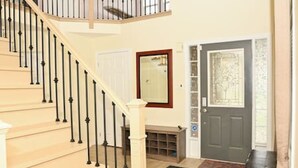 A staircase with black balusters, a wooden door with a glass panel, and a small bench. - The Peaceful Court House in Kitchener (Kitchener)