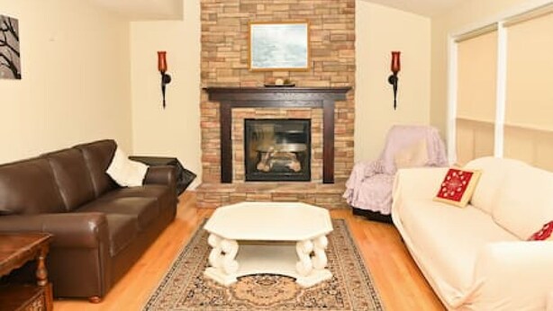 A living room with a fireplace, a brown leather sofa, a white sofa, and a coffee table. - The Peaceful Court House in Kitchener (Kitchener)