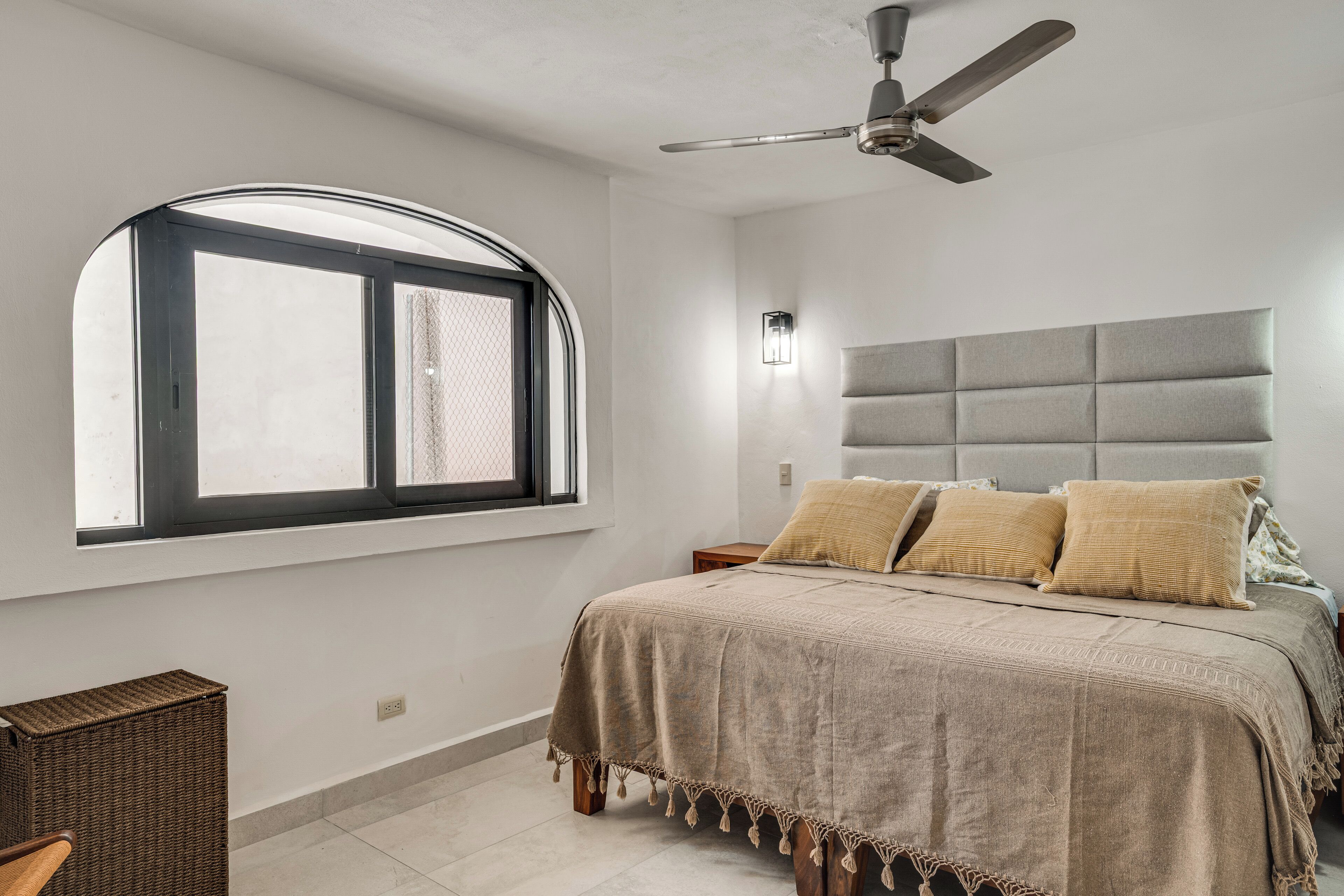 A bedroom with a bed, a window, a ceiling fan, and a nightstand.