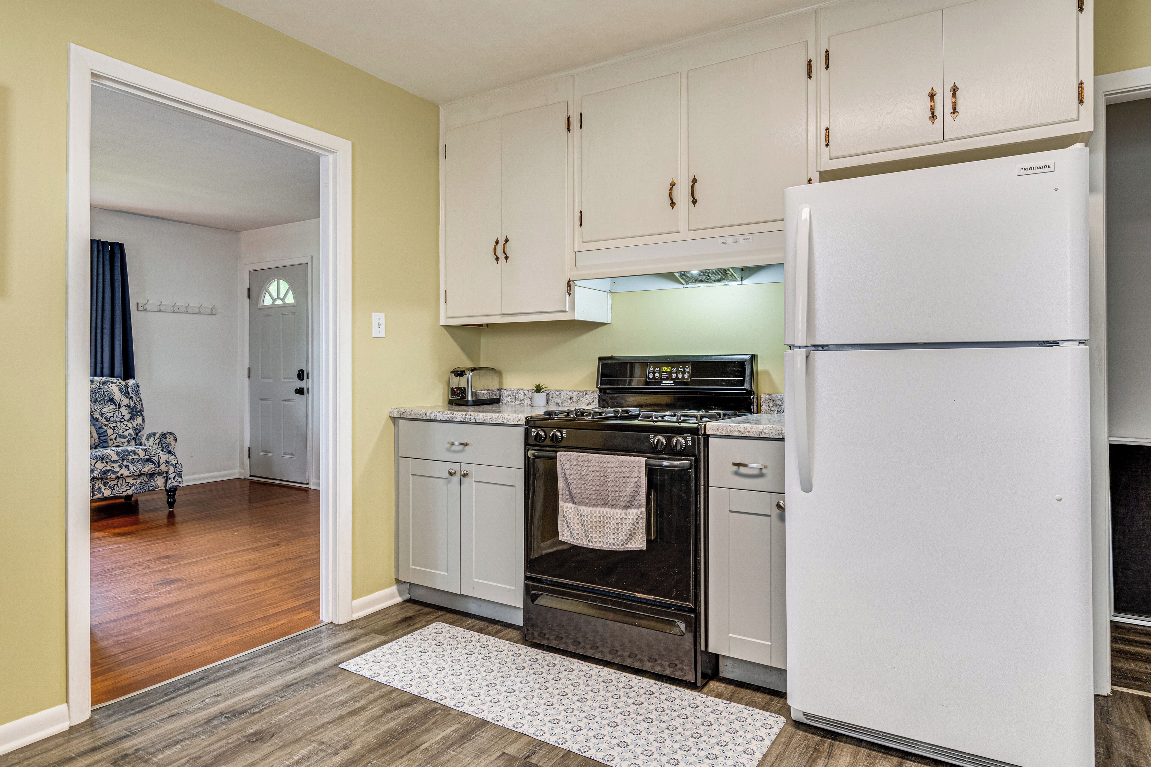 A kitchen with white cabinets, a black stove, and a white refrigerator.