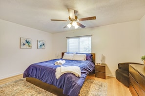 A bedroom with a bed, a ceiling fan, a nightstand, a desk, and a window. - All-season Base in West Valley City, Pets Welcome! (West Valley City)