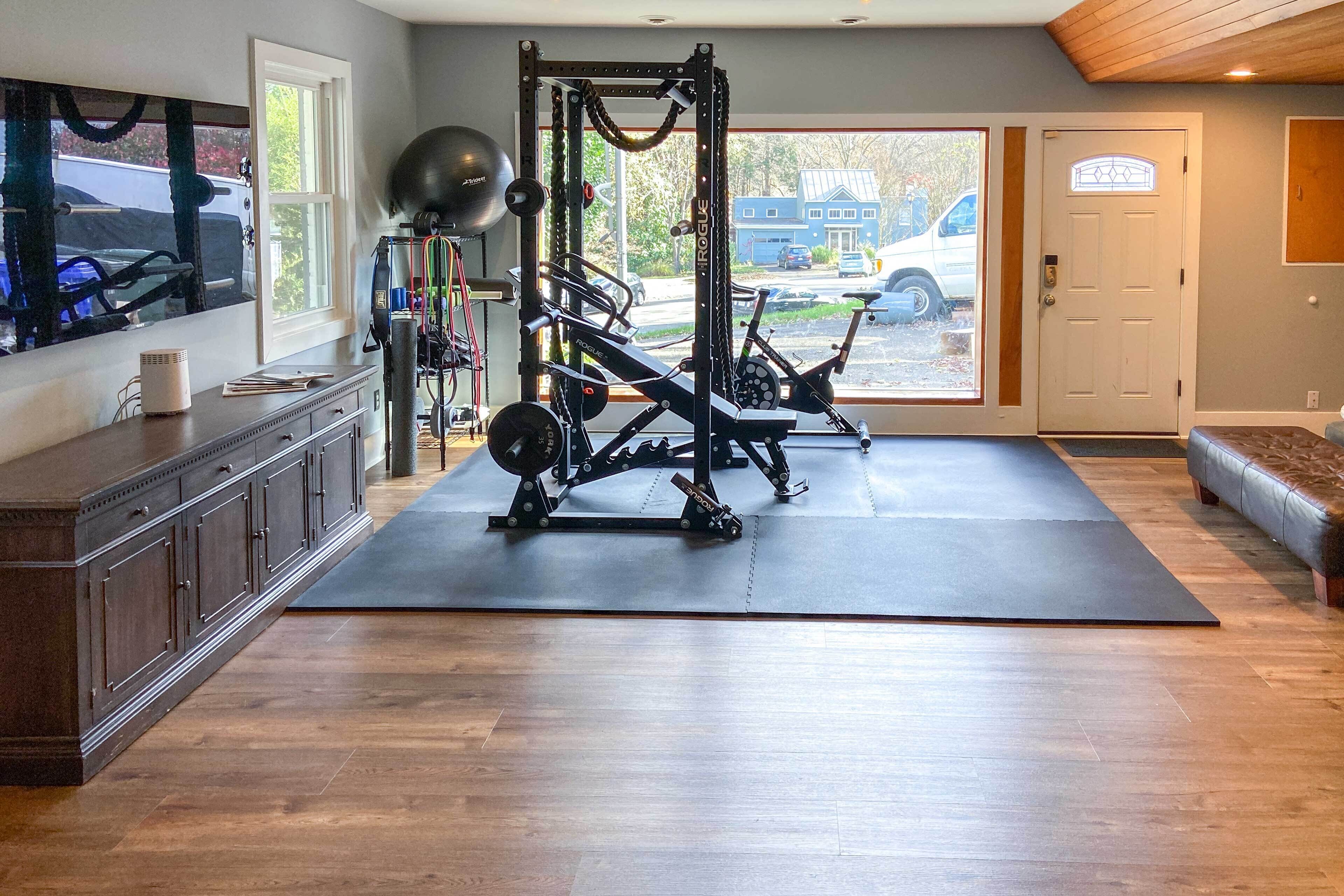 A home gym with a weight bench, squat rack, and exercise balls.