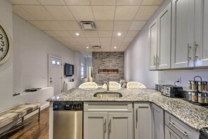 Una cocina moderna con encimeras de granito, electrodomésticos de acero inoxidable y un salpicadero de piedra.
