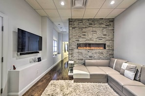 Una sala de estar moderna con una pared de acento de piedra, una chimenea, un televisor de pantalla plana grande y un sofá seccional.