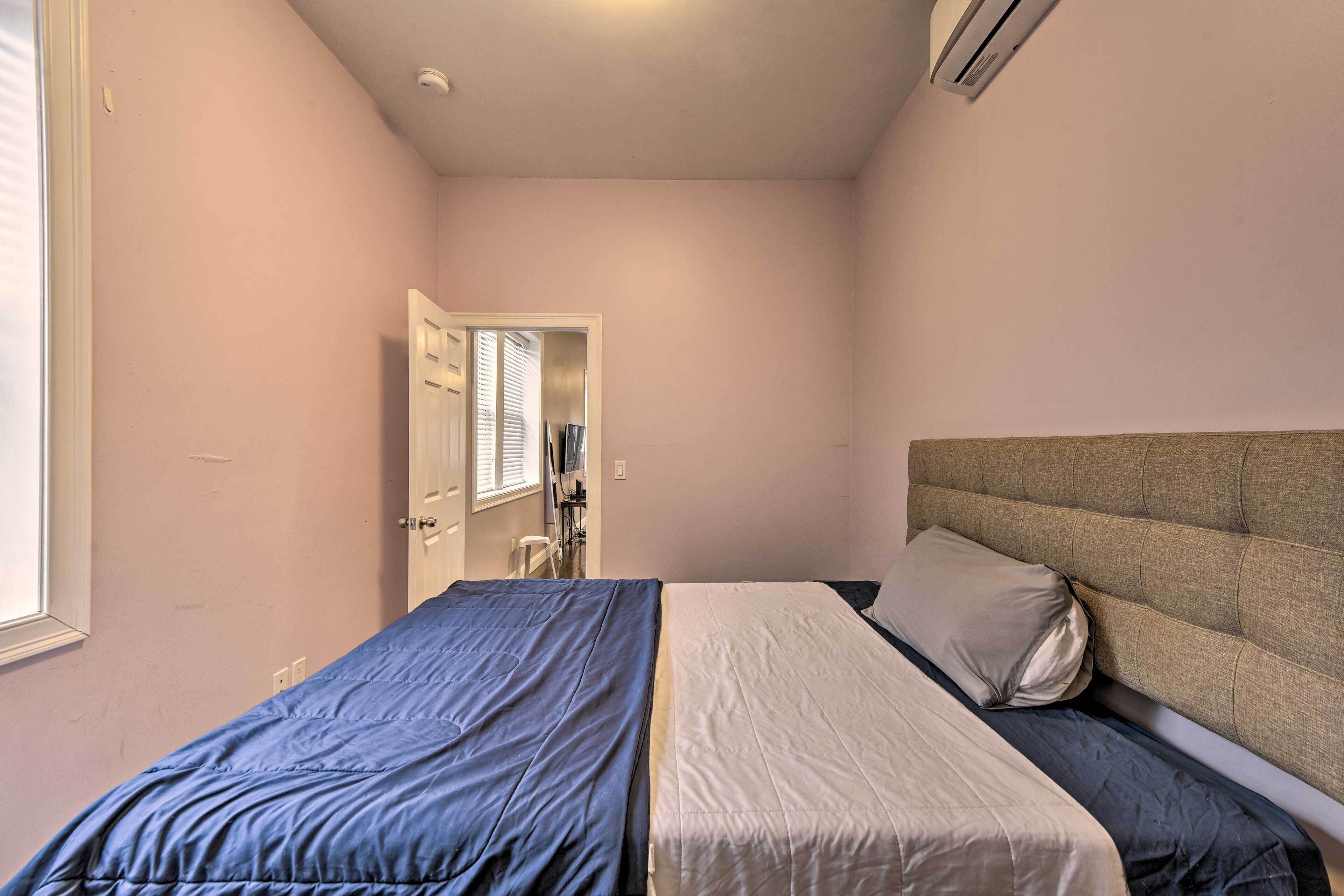 A bedroom with a bed, a headboard, and a window.