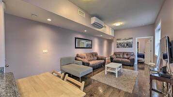 A living room with a wooden dining table, two brown leather sofas, a patterned sofa, and a white coffee table.