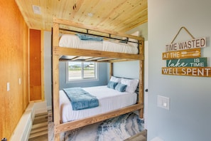 A bunk bed room with a wooden ceiling, a window, and a motivational quote on the wall.