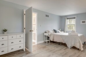 A bedroom with a bed, bedside table, dresser, and a window. - Kayaks, Paddleboat! Lakefront Retreat in Barnstead (Center Barnstead)