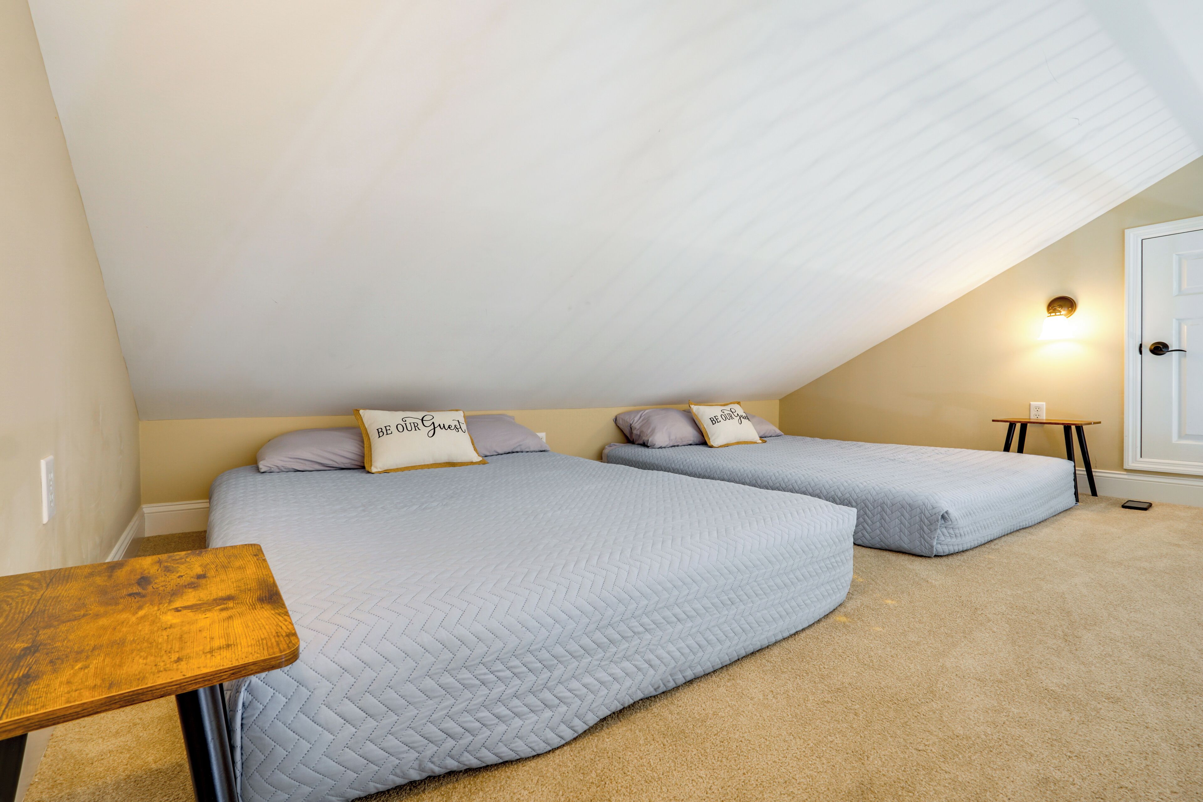 A bedroom with two beds, a small table, and a light fixture.