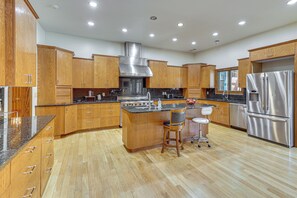 A modern kitchen with wooden cabinets, stainless steel appliances, and a central island with stools. - Stocked Pond! 33-acre Lagrange Estate w/ 2 Units (LaGrange)