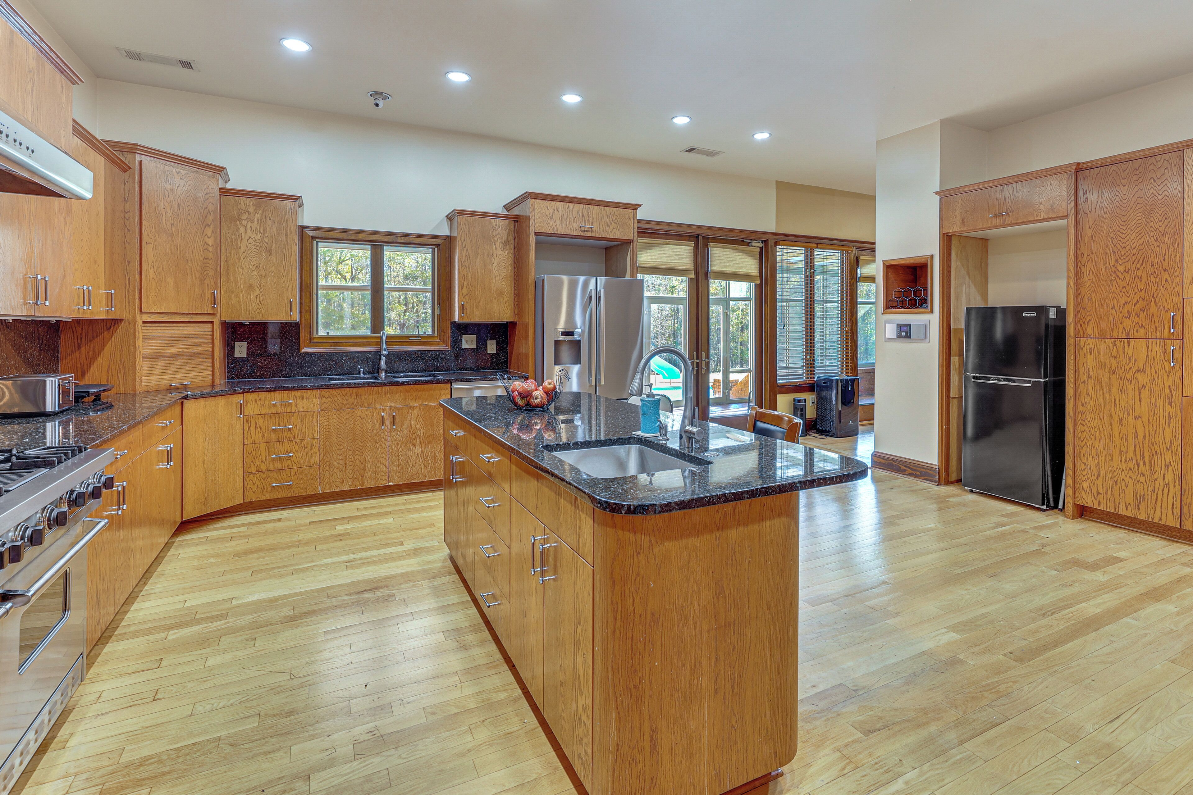 A modern kitchen with wooden cabinets, a granite countertop, stainless steel appliances, and a large island.