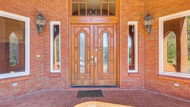 A brick building with a wooden double door, two arched windows, and a black doormat. - Stocked Pond! 33-acre Lagrange Estate w/ 2 Units (LaGrange)