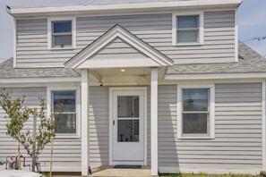 A two-story house with a front porch, a small tree, and a visible garage door. - Walkable + Convenient! 1st-floor Apt in Middletown (Middletown)