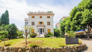 A two-story building with a central entrance, a stone wall surrounding the property, and a paved area in front. - The Riviera apartment, located on the ground floor of Villa Aranci in Via Fabio Filzi 2B, Genoa, offers an elegant and comfortable stay in an exclusive setting.With a private entrance, double bedroom, living area, private bathroom, and direct access to t (Genova)