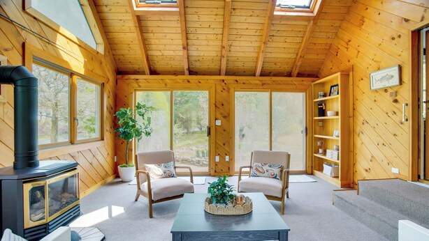A cozy cabin interior with a fireplace, two armchairs, a coffee table, and a bookshelf. - 3 Mi to Nauset Beach! Family Home w/ Private Yard (Orleans)