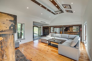 A spacious living area with a large sectional sofa, wooden flooring, and a modern ceiling design. - 90-acre Gem w/ Custom Pool & 2 Ponds in Jefferson (Jefferson)