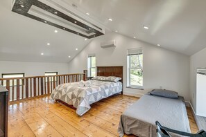 A bedroom with a large bed, a smaller bed, wooden flooring, a balcony, and a sloped ceiling with recessed lighting. - 90-acre Gem w/ Custom Pool & 2 Ponds in Jefferson (Jefferson)