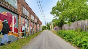 A narrow street with a brick building on one side featuring colorful murals. - Walk to Everything! Dtwn Hudson Apartment (Hudson)